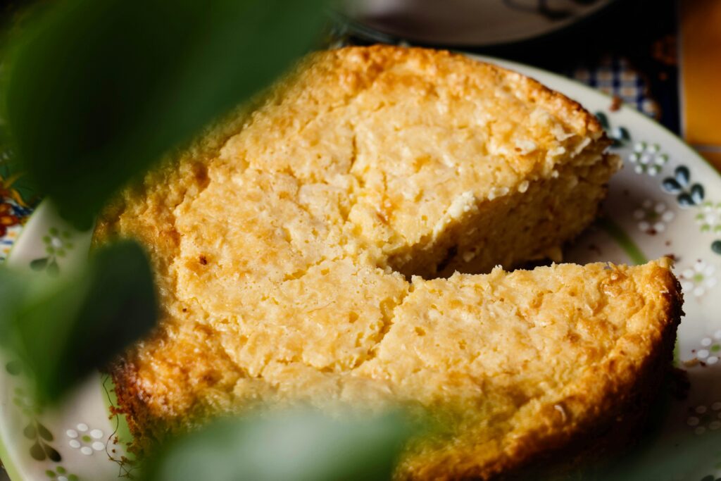 Close-up of a homemade elote cake with a missing slice on a decorative plate.