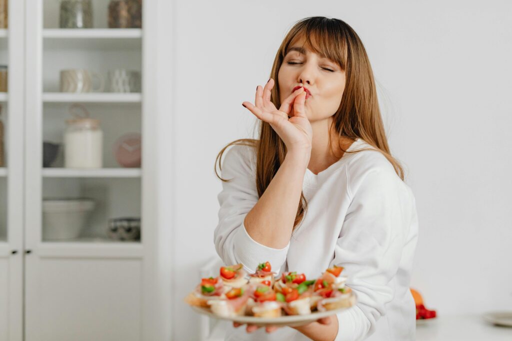 Woman savoring delicious bite-sized treats in a modern kitchen setting.